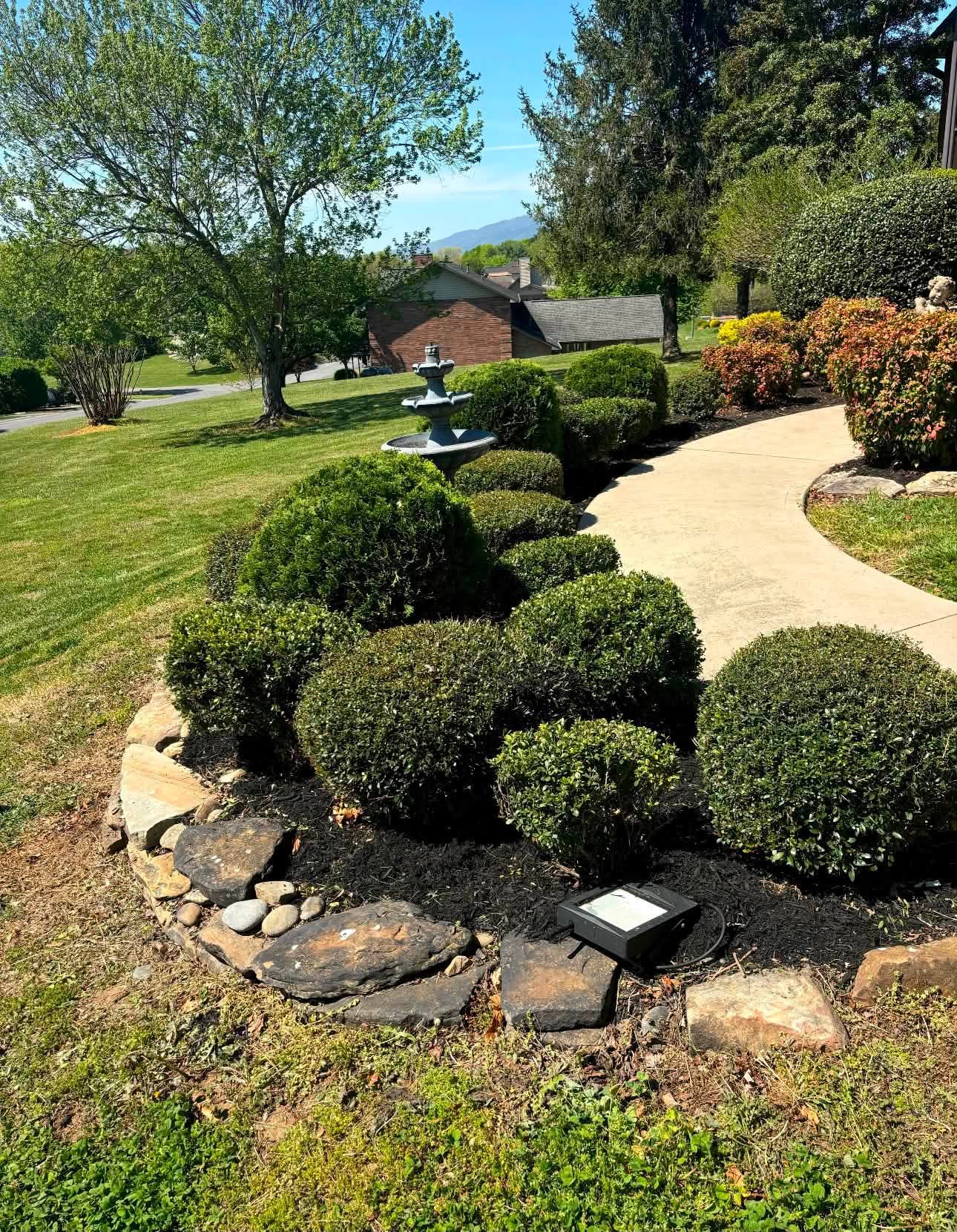 Sculpted boxwood beds and fountain along a curved walkway