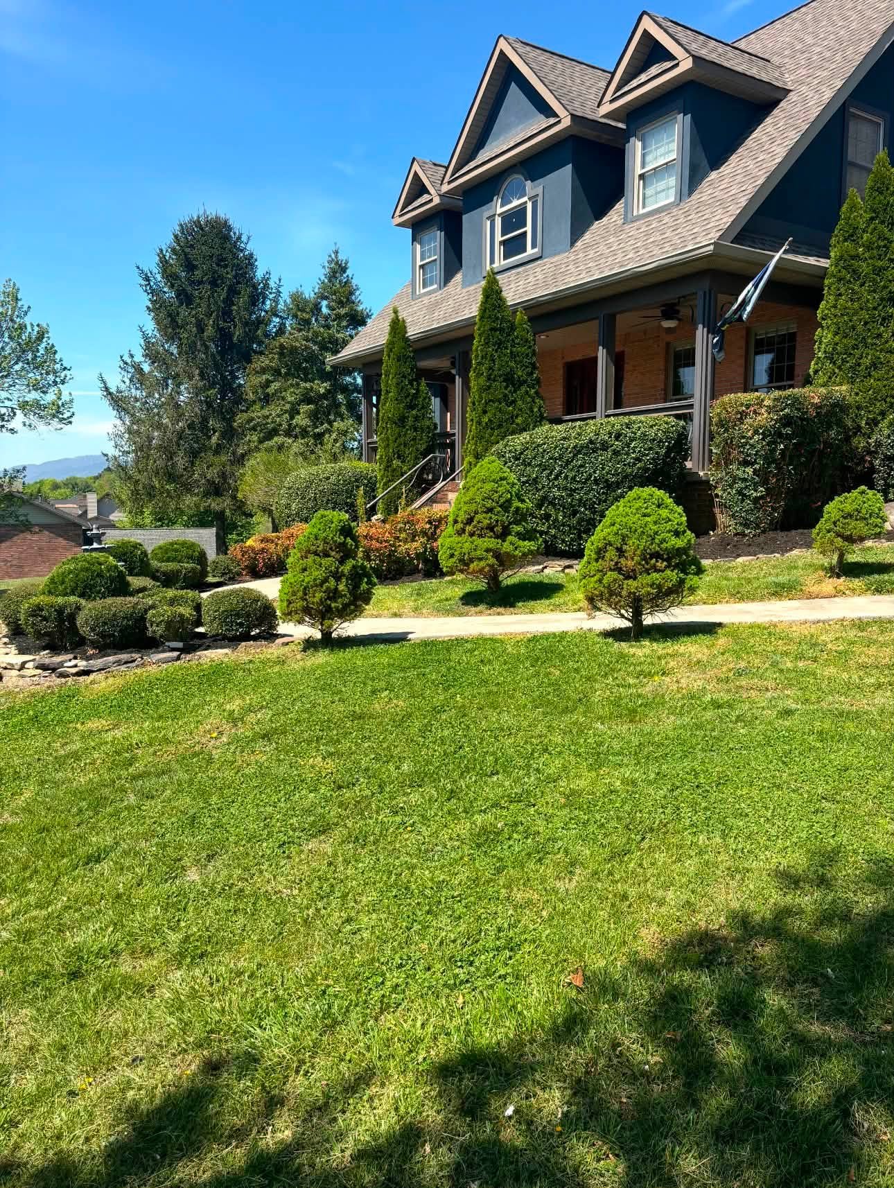 Manicured front lawn and shaped shrubs at a Knoxville home maintained by HomeVibes